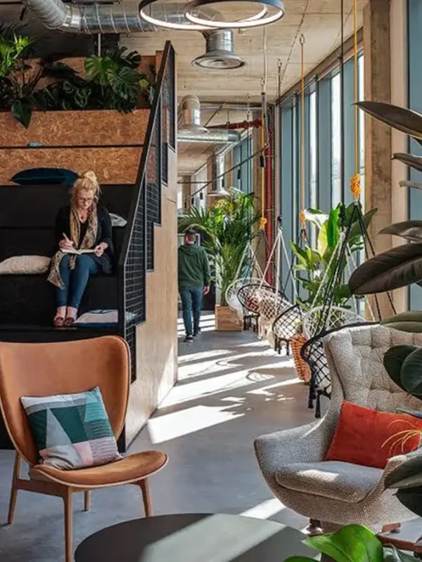 Pomieszczenie do co workingu z przyjemnymi fotelami, zielenią oraz dużą ilością światła