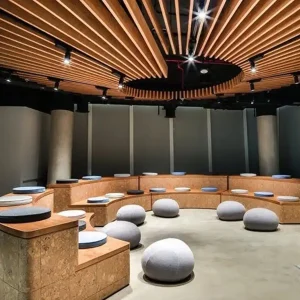 Sala konferencyjna bądź lekcyjna w stylu boiler room z pufami oraz miękkimi siedziskami na bazie okręgu