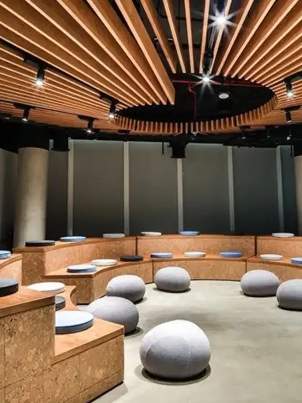 Sala konferencyjna bądź lekcyjna w stylu boiler room z pufami oraz miękkimi siedziskami na bazie okręgu